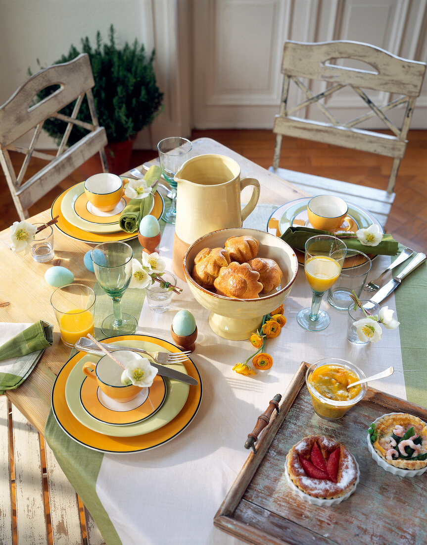 Breakfast table set for Easter with ranunculus and anemones, elevated view
