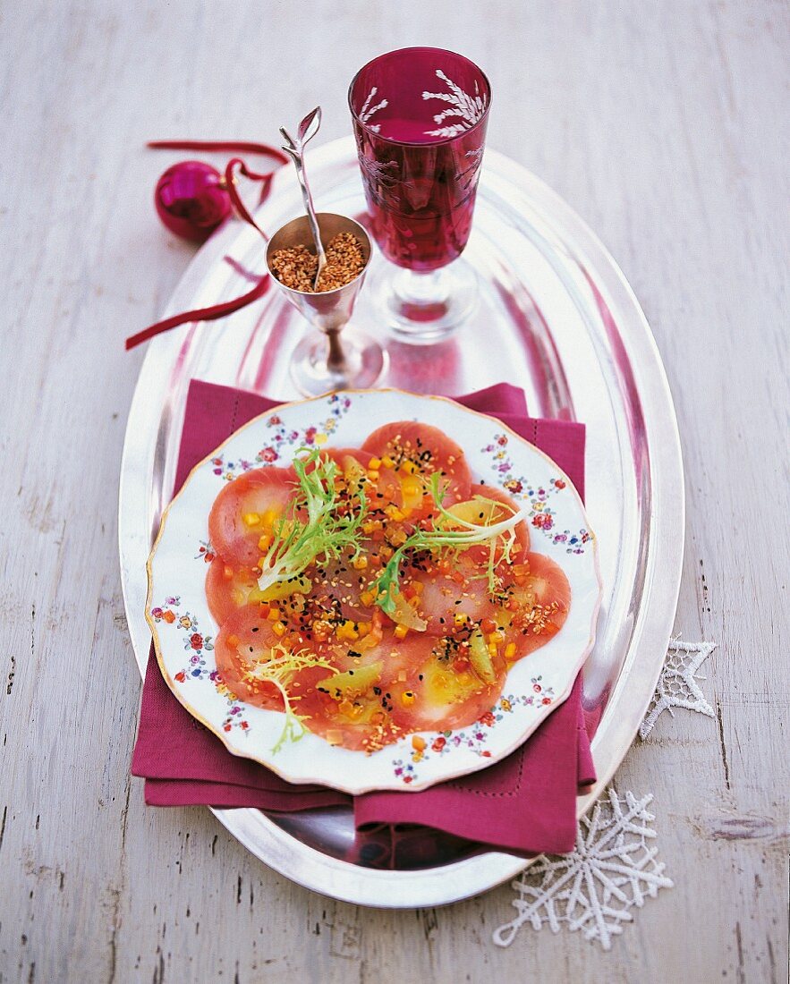 Fine fish carpaccio with sesame seeds on a table decorated for Christmas