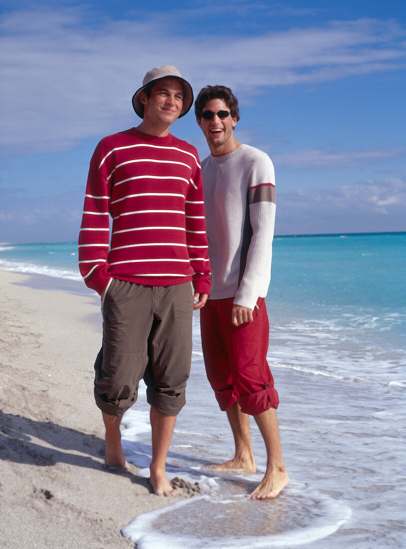 Two men in casual standing on beach and smiling