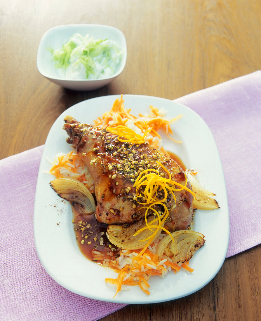 Turkey leg with rice, onions and orange sauce on plate