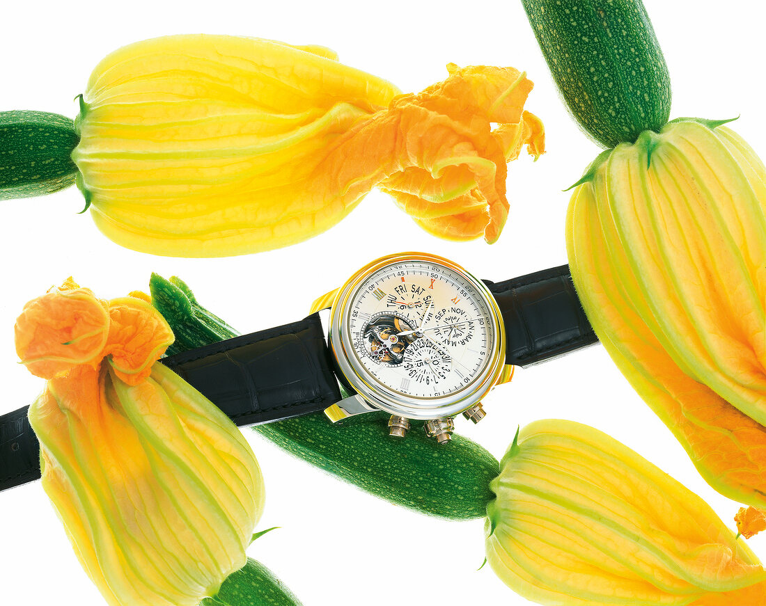 Luxury wrist watch with zucchini blossoms against white background