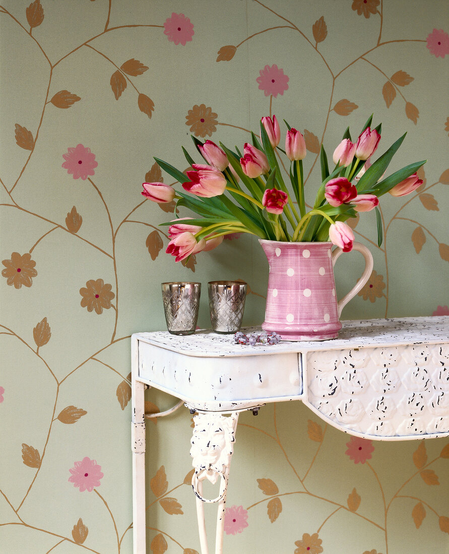 Table with tulip vase against floral wallpaper