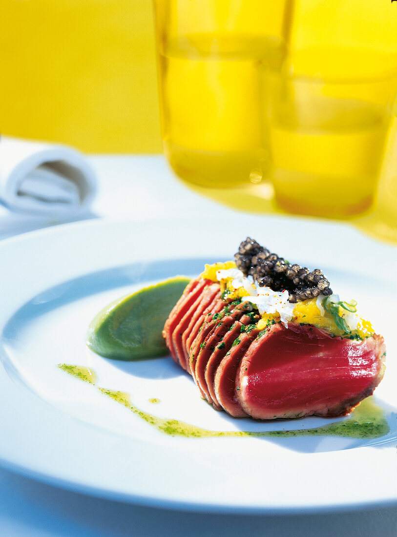 Raw tuna with caviar drizzled with herb vinaigrette on plate