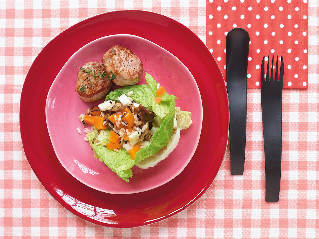 Seven-grain risotto in savoy cabbage leaf on red plate with plastic cutlery