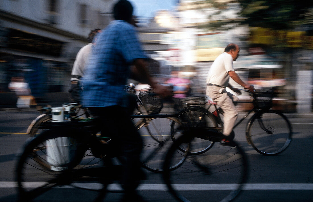 Men riding bicycle on street in Shanghai, China, blurred