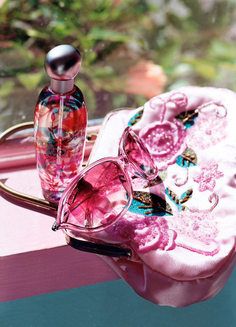 Close-up of sunglasses, perfume bottle and handbag