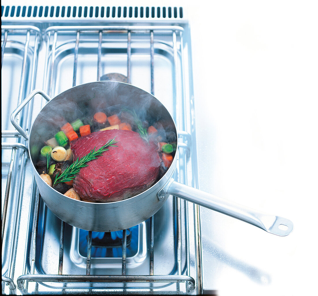 Roast beef cooked with vegetables and rosemary in saucepan