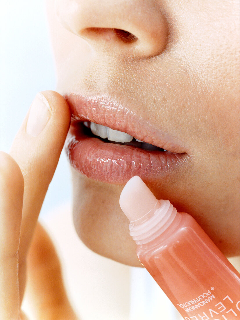 Close-up of woman applying gloss on lips