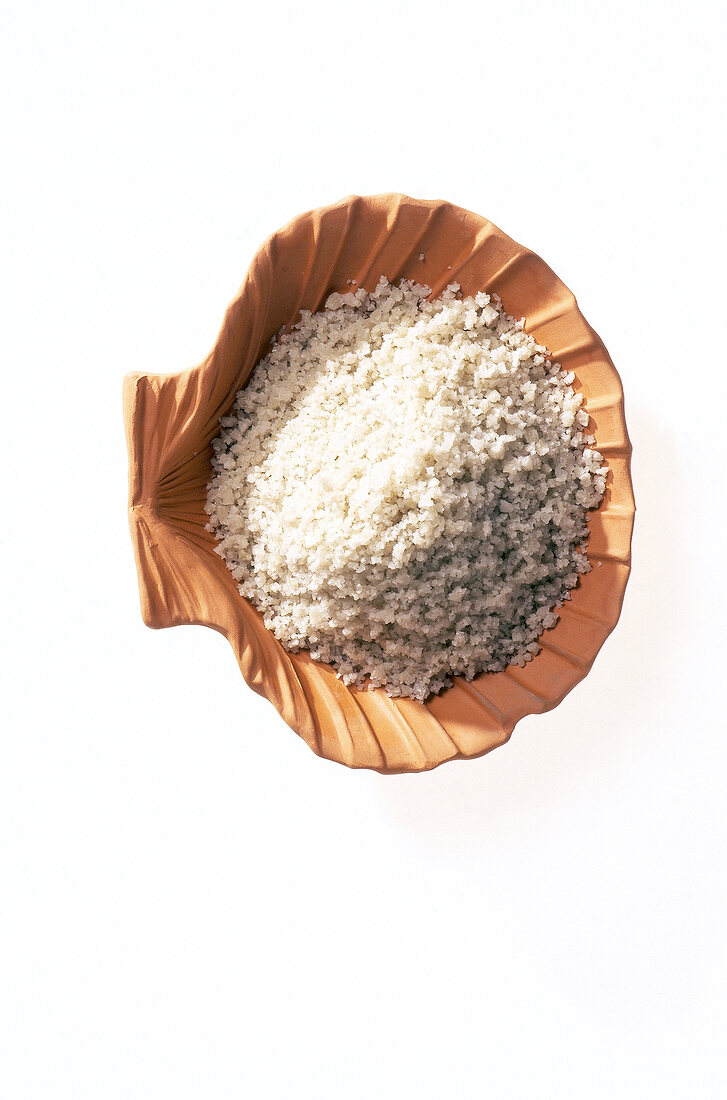 Close-up of bath salt in ceramic shell on white background