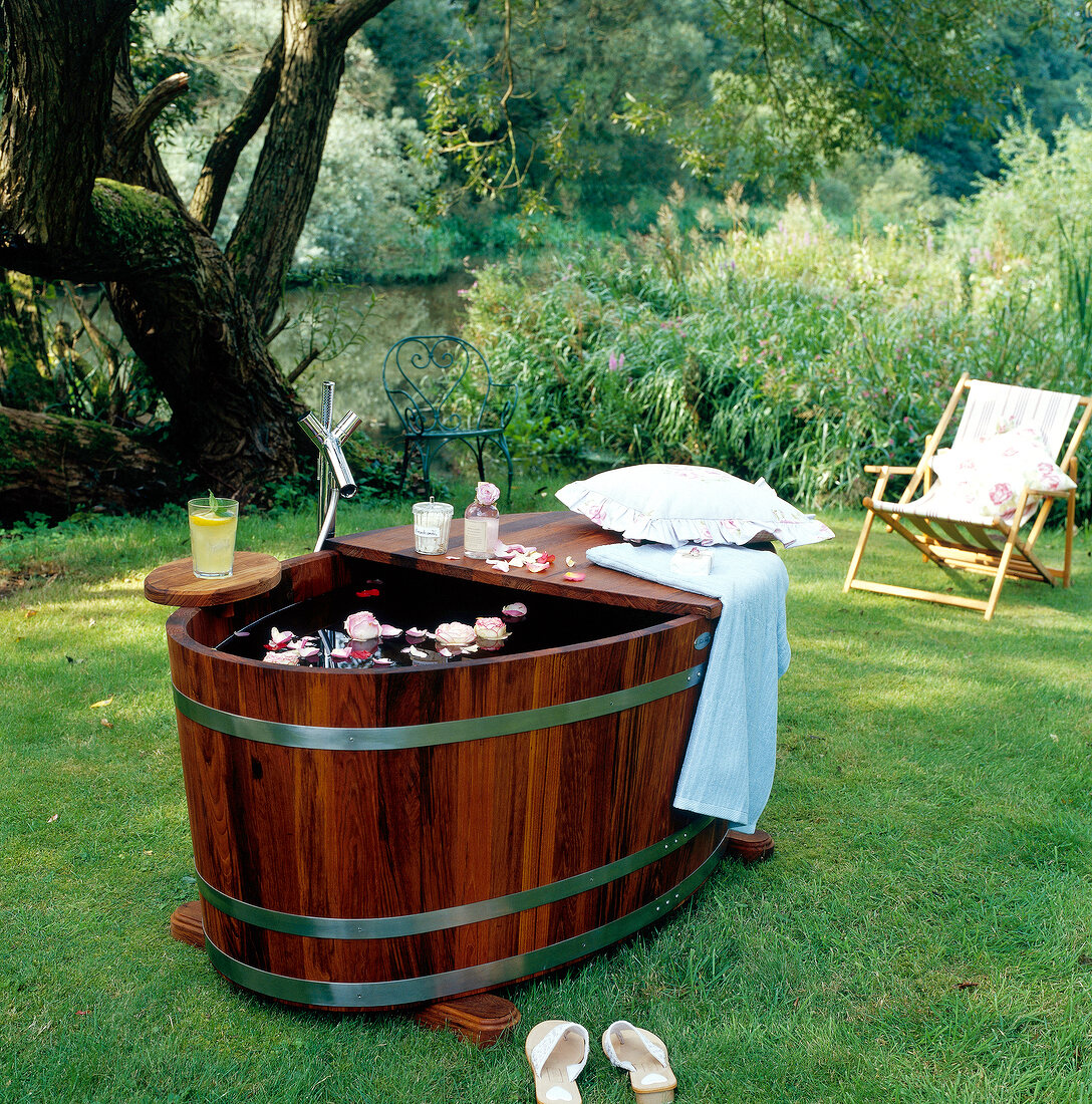 Holzwanne im Garten, schwimmende Blüten