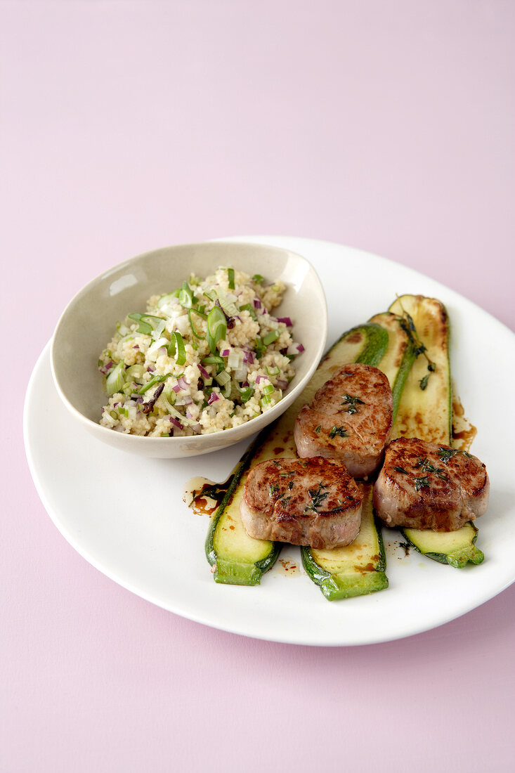 Pork in plate with bowl of couscous