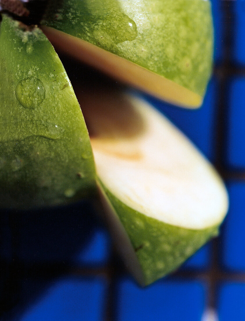 Grüner Apfel mit Wassertropfen und einem herausgeschnittenen Stück