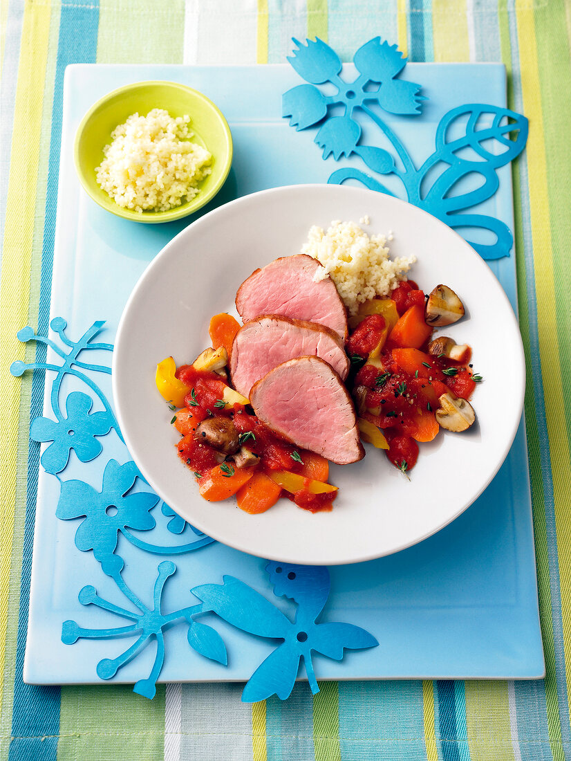 Pork with tomato sauce served with rice and vegetables on plate