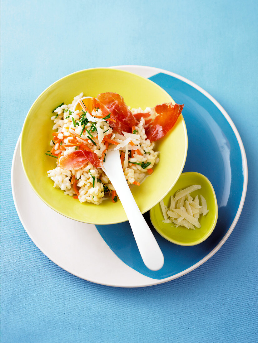 Carrots and herb risotto with ham in bowl