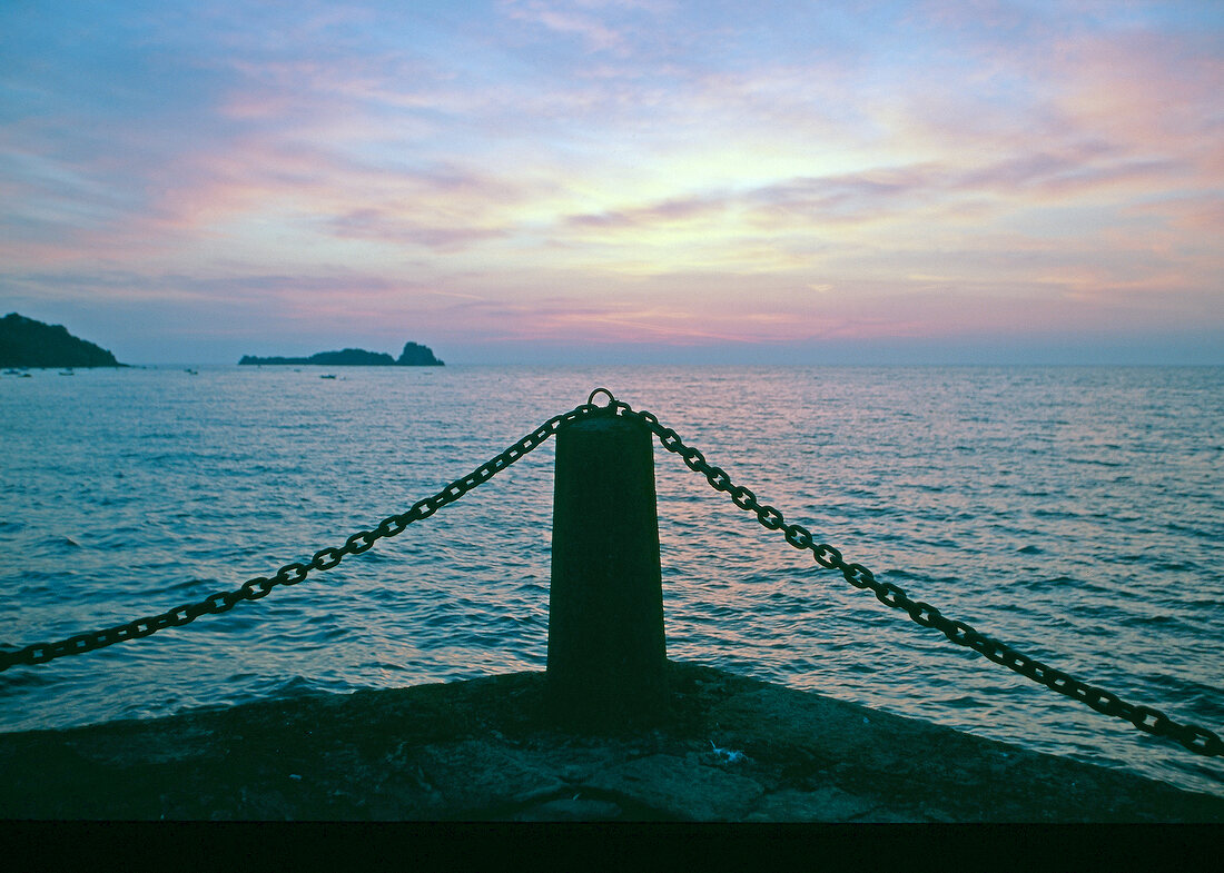 View of pole on pier near sea at sunset, Brittany