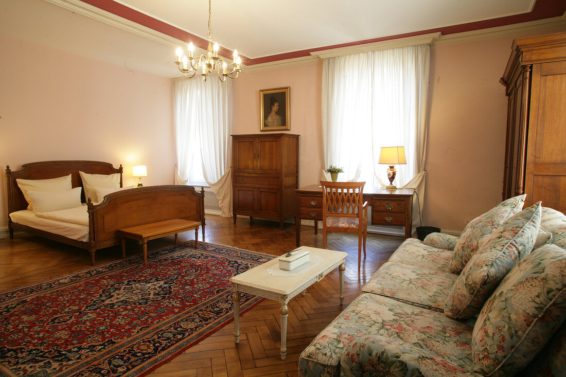 Bedroom with bed, cushion, chairs and sofa in hotel, Germany