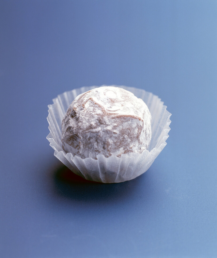 White creamy praline in muffin cup on blue background