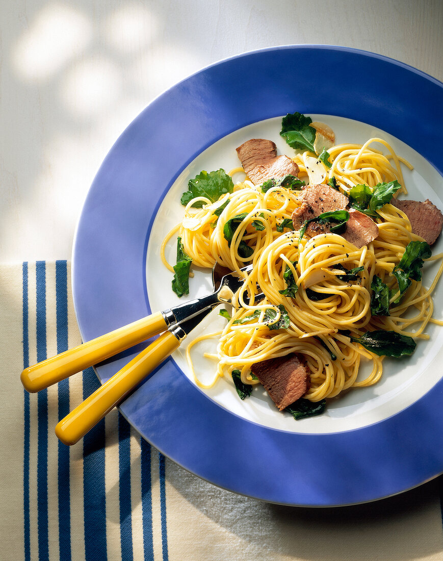 Spaghetti with lamb fillet and rocket on plate