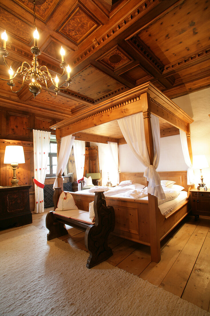 Bedroom with wooden poster bed and chandelier in hotel, Austria