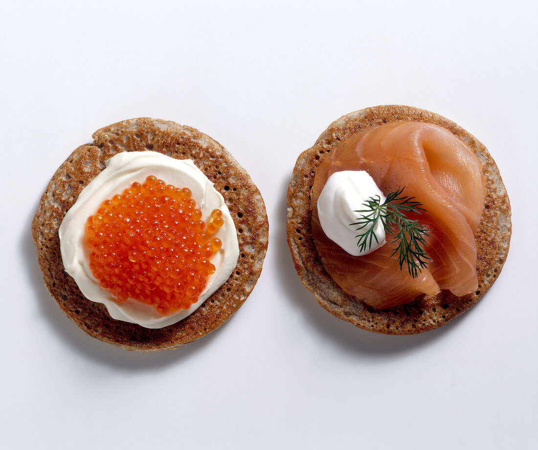 Blinis with smoked salmon, salmon caviar and sour cream on white background