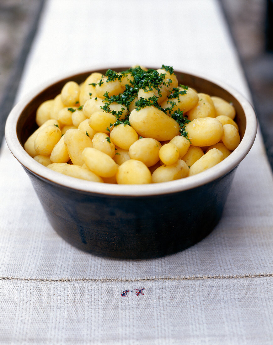 Close-up of boiled potatoes garnished with chopped parsley in bowl