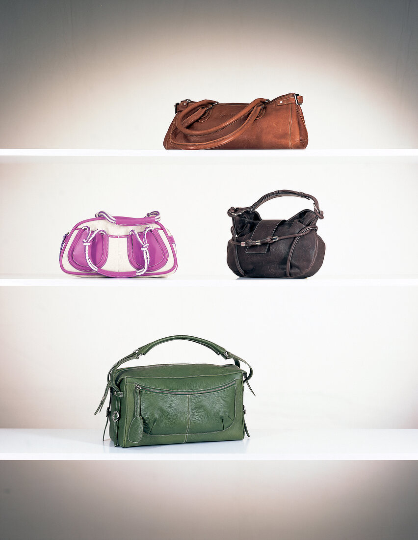 Four different handbags on white display rack