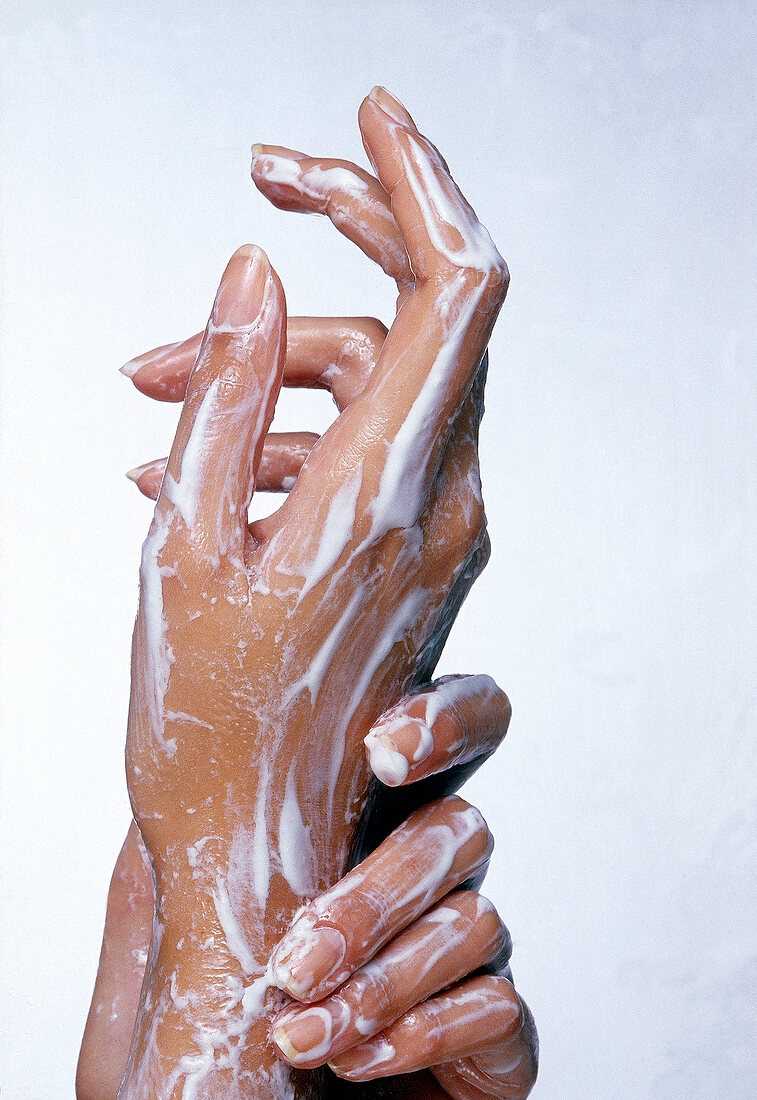 Close-up of woman's hands covered with cream