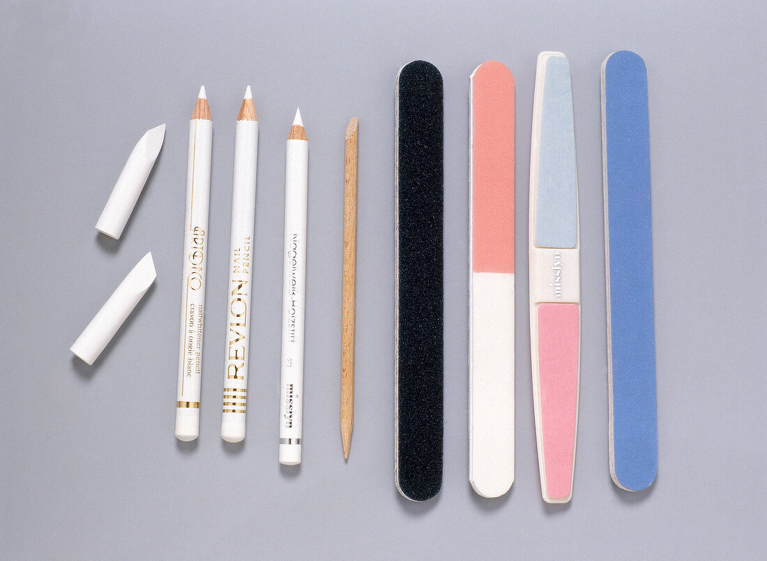 Assortment of white pencils and nail files for manicure on gray background