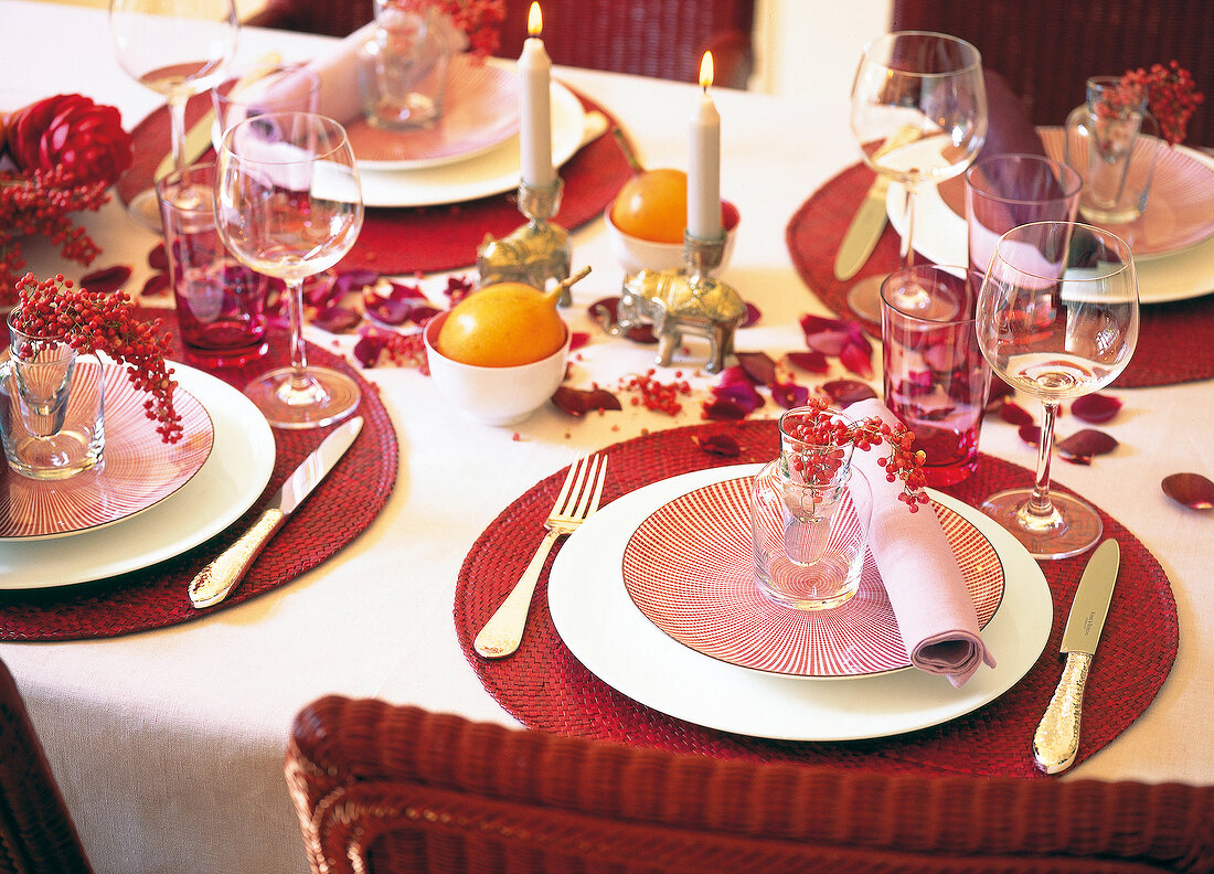 Decorated red dinning table with lit candles and petals