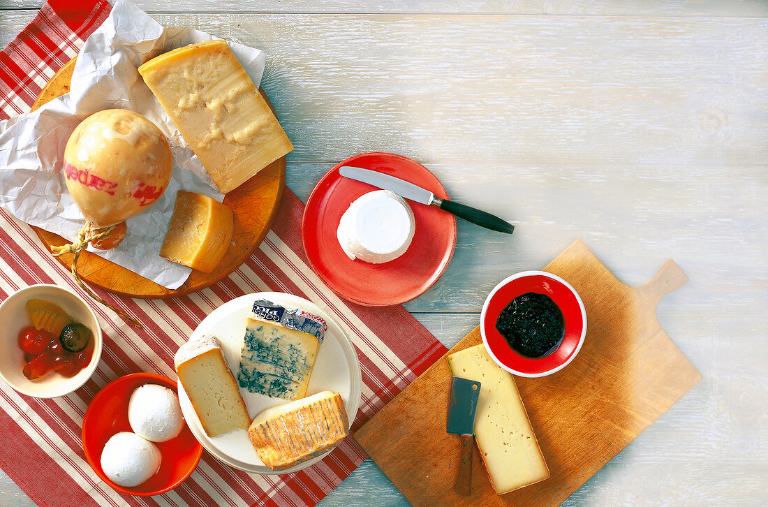 Variety of Italian cheeses and mustard fruits with knife on wooden surface