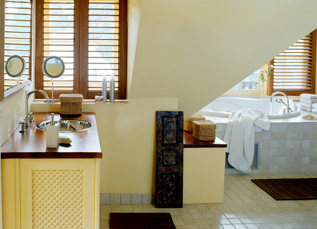 Vanillefarbenes Badezimmer unterm Dach, mit Marmor gefliest.