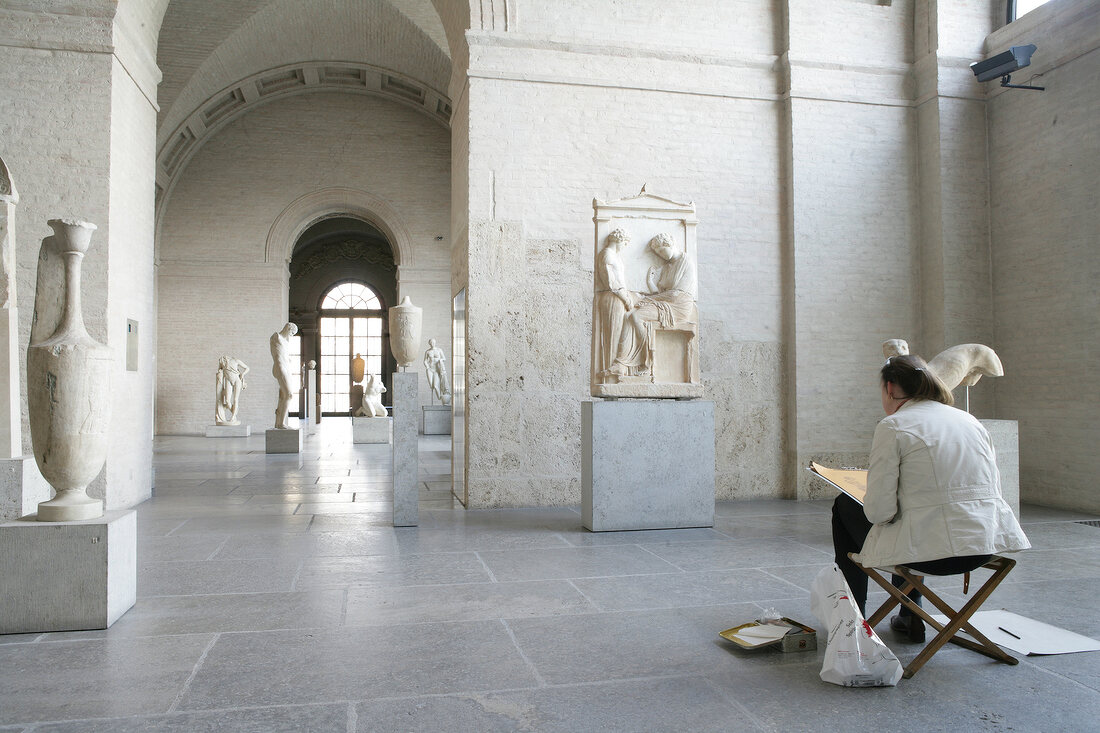 Woman sitting in front of sculptures in Glyptothek Museum, Munich, Germany