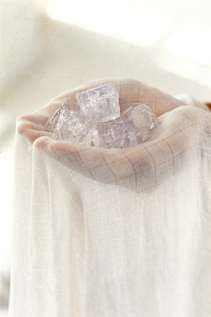 Close-up of a person's hands holding ice cubes in white towel