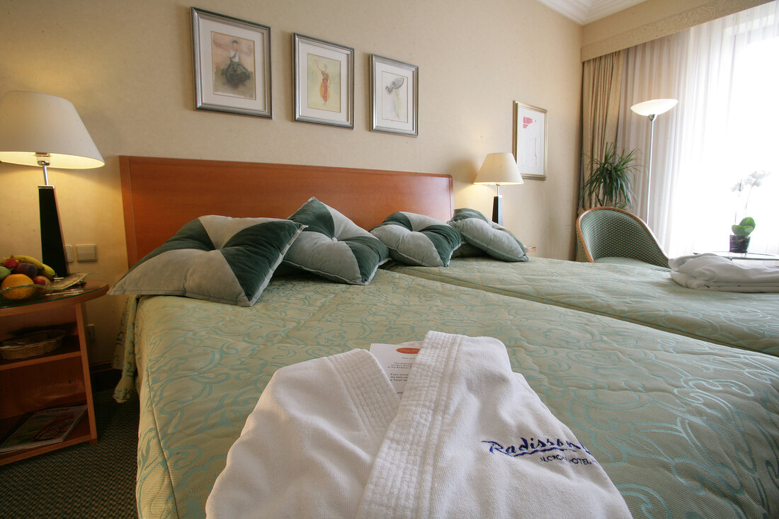 View of luxurious hotel bedroom with bathrobe on bed, Czech Republic