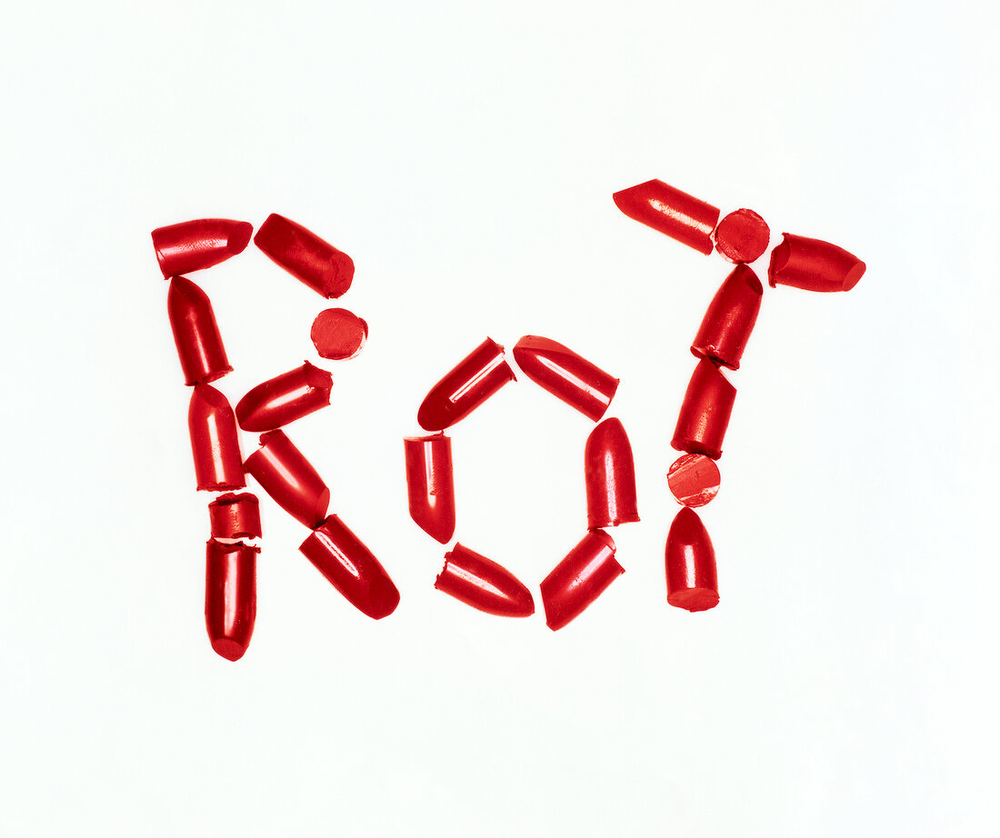 Pieces of red lipstick placed together to form word 'rot' on white background