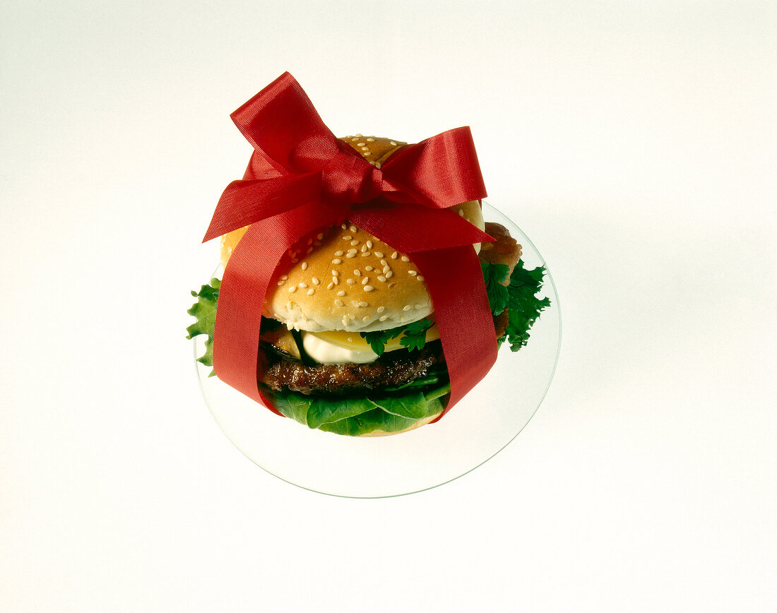 Burger decorated with red ribbon on white background