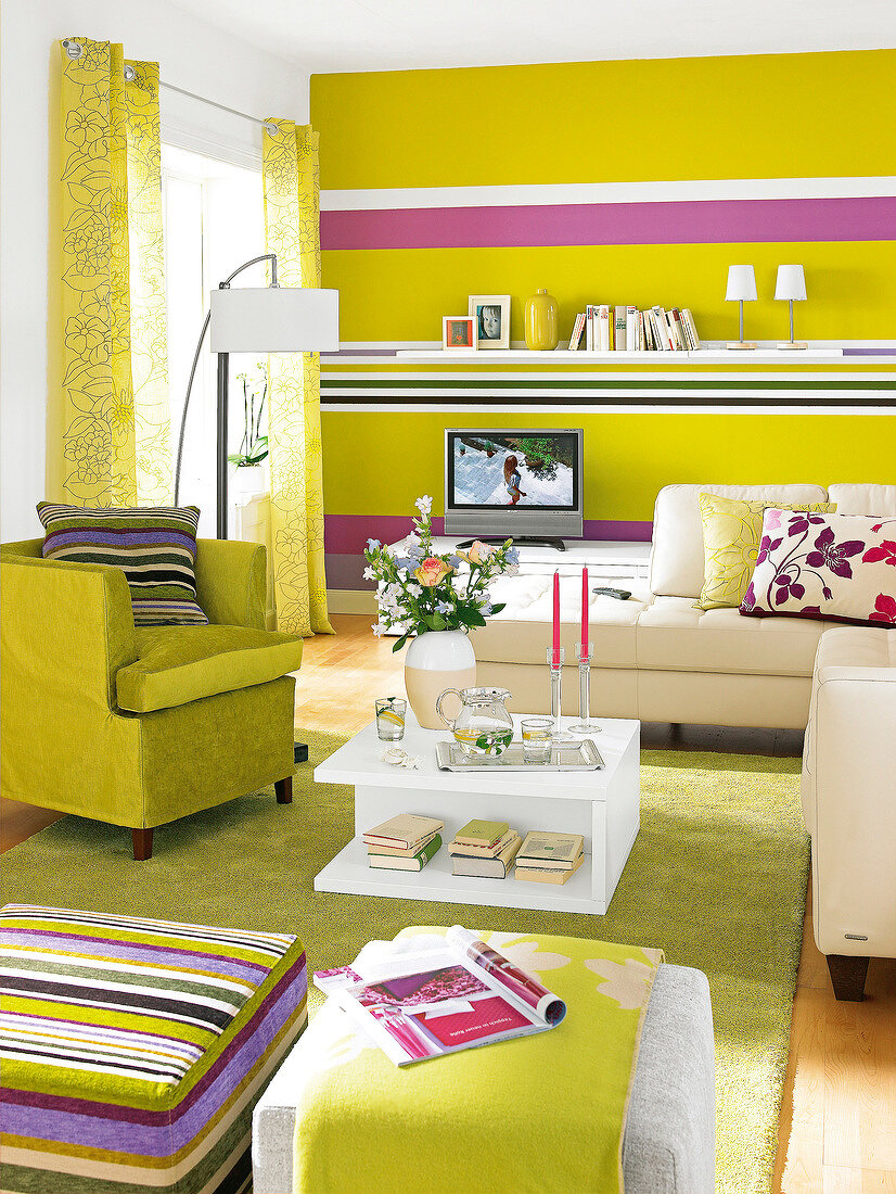 Wohnzimmer mit grünem Sessel und hellem Sofa, Wand + Teppich grün