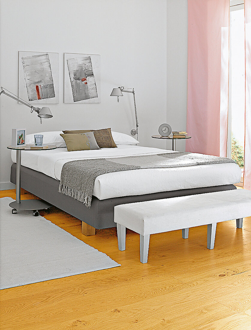 Schlafzimmer mit hellem Bett in Grau Hocker in weiß