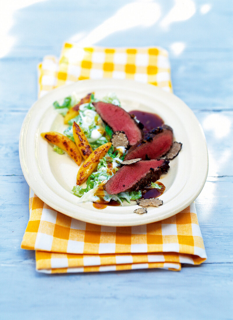 Venison with potatoes, cabbage and truffles on plate