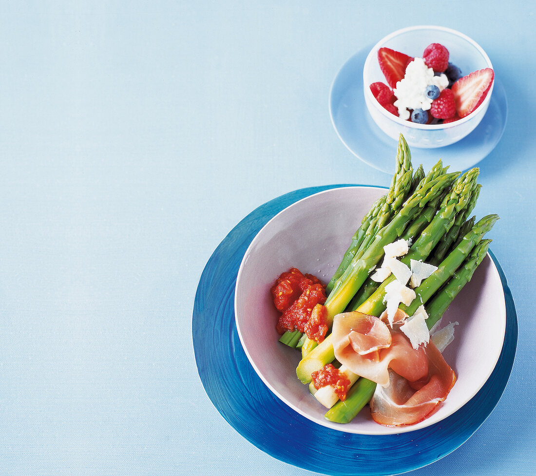 grüner Spargel mit Tomaten und Katenschinken, daneben Beerensalat