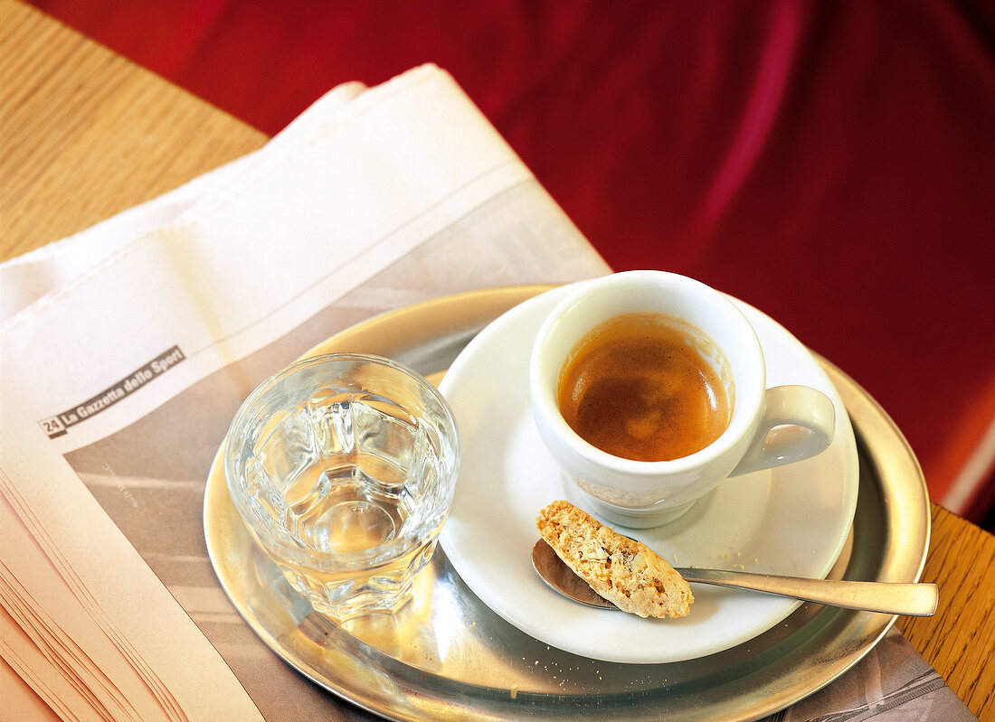 Espresso und Glas Wasser auf einem silbernen Tablett