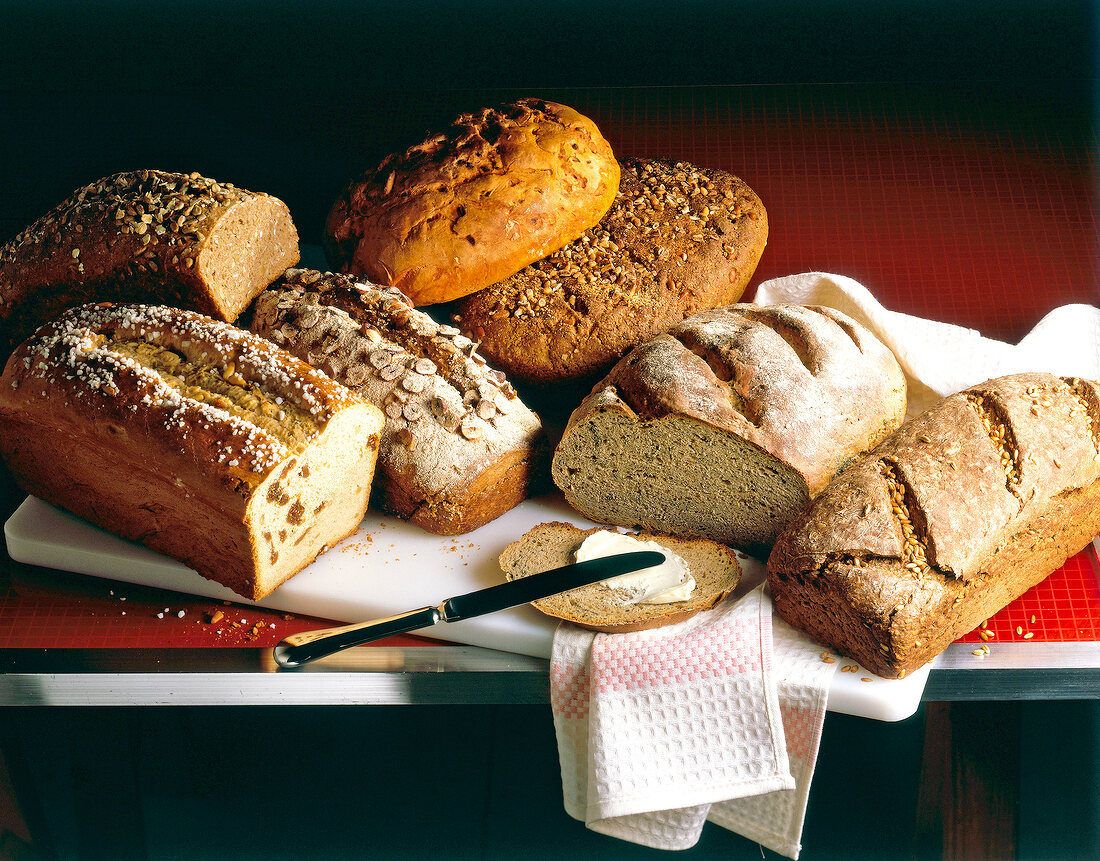 Different types of whole wheat bread loaves and slice with butter