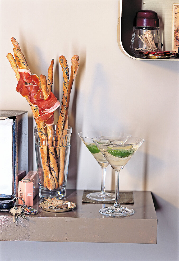 Grissini breadstick with parma ham and glass of wine on table