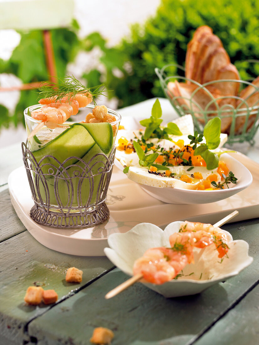 Glass of cucumber gazpacho with shrimp, marinated feta cheese on plate