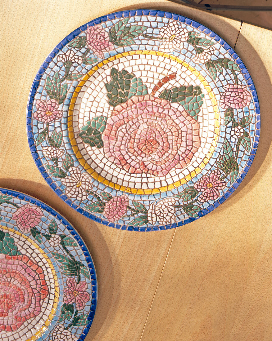Colourful mosaic plate with rose pattern on wood