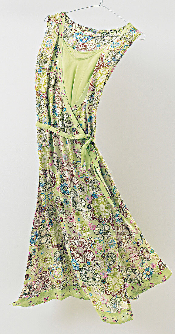 Floral pattern green viscose summer dress hanging on coat hanger