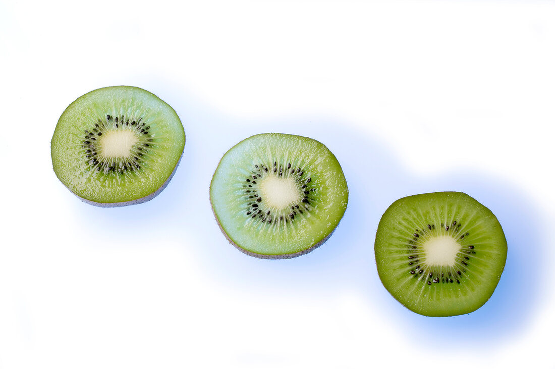 Three half kiwi on white background