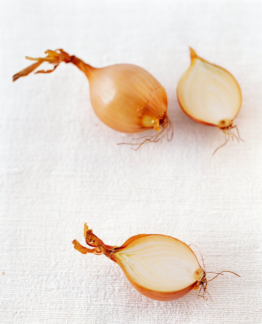 Whole and halved raw onion on white background
