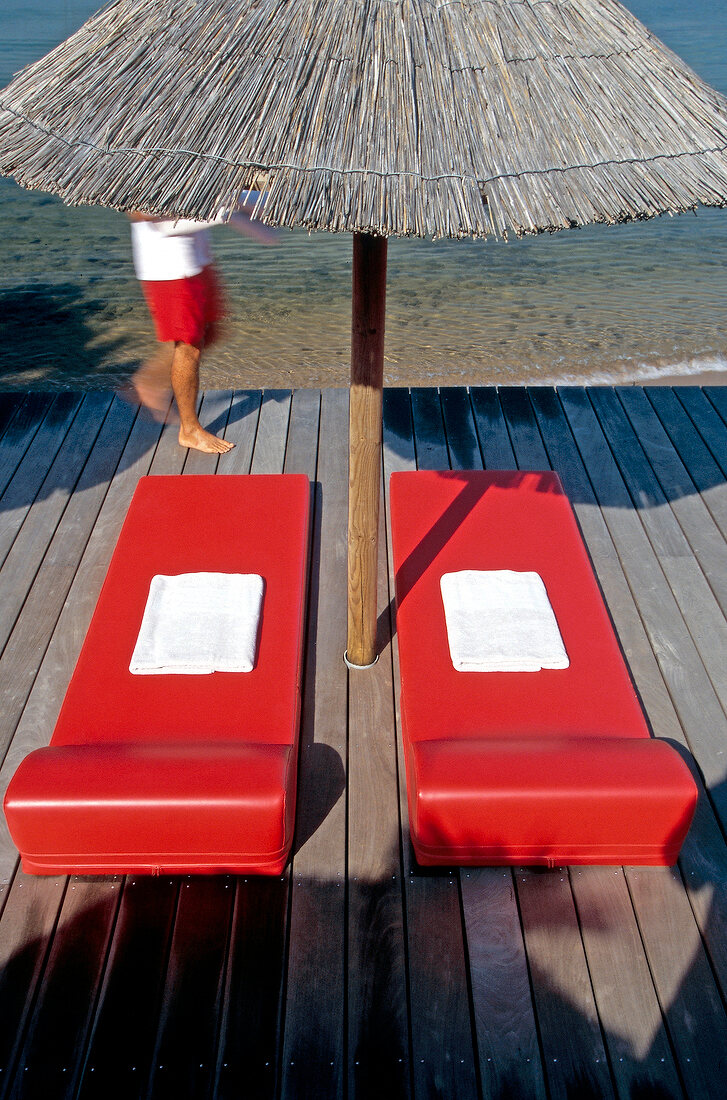 Red sun loungers and beach umbrella at Hotel Casadelmar, Porto Vecchio, Corsica, France