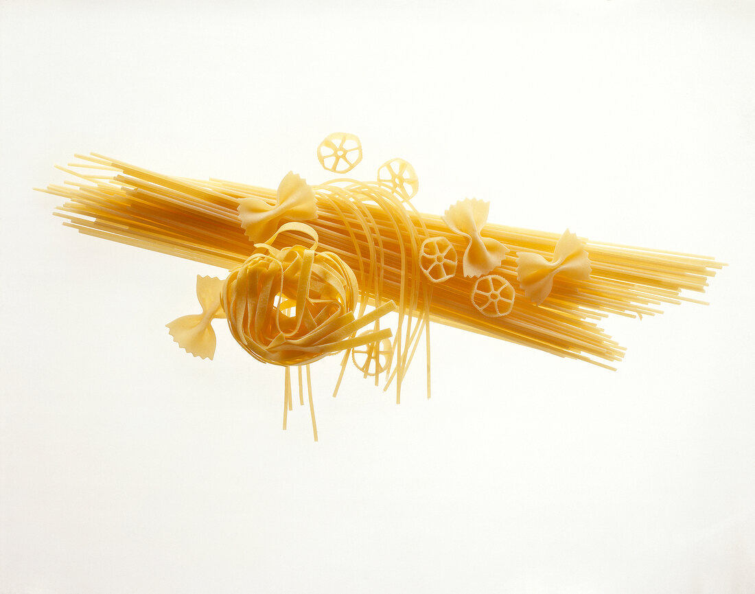 Raw pasta, spaghetti and butterfly noodles on white background